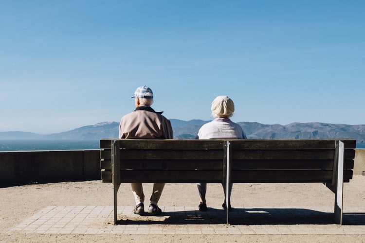 An older couple sitting together on a bench.