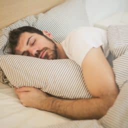 A man sleeping while holding a pillow in bed.
