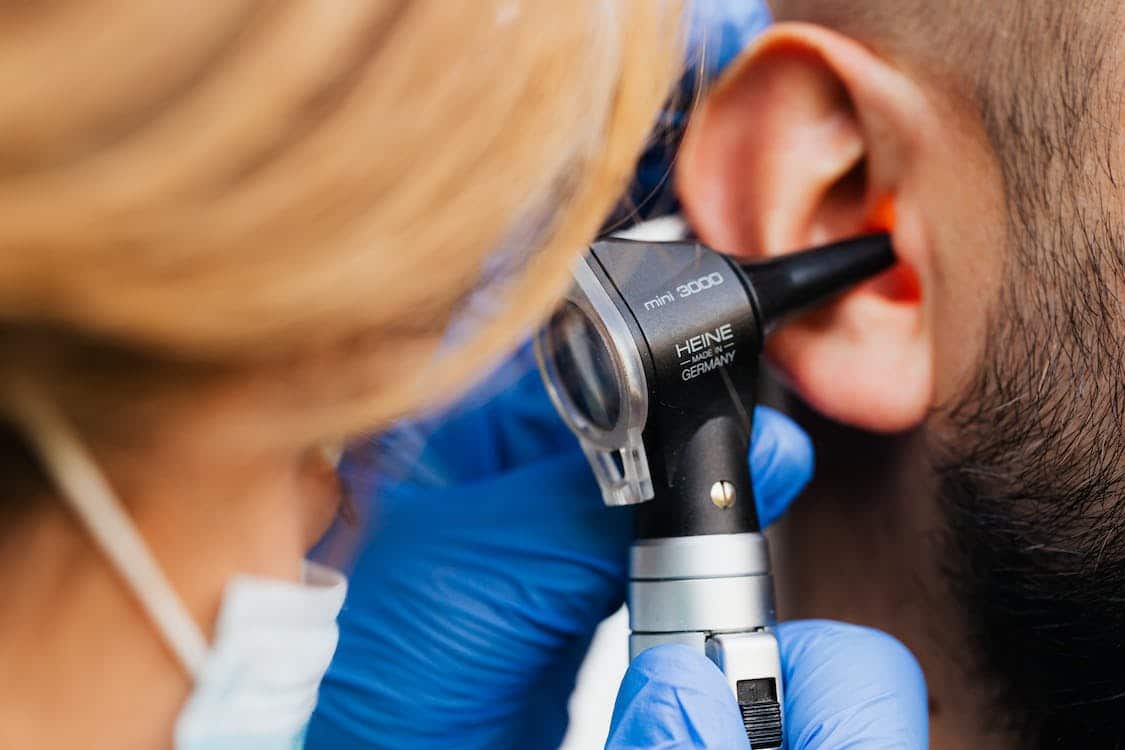 A hand holding an otoscope into an ear.