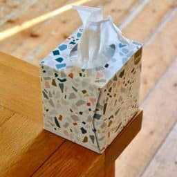 A box of tissues on a wooden counter.