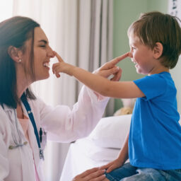 Doctor and young boy laughing and touching each other's noses.